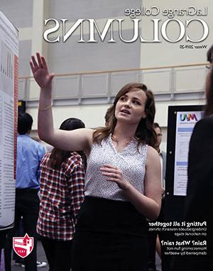 female gestures to her poster at a conference
